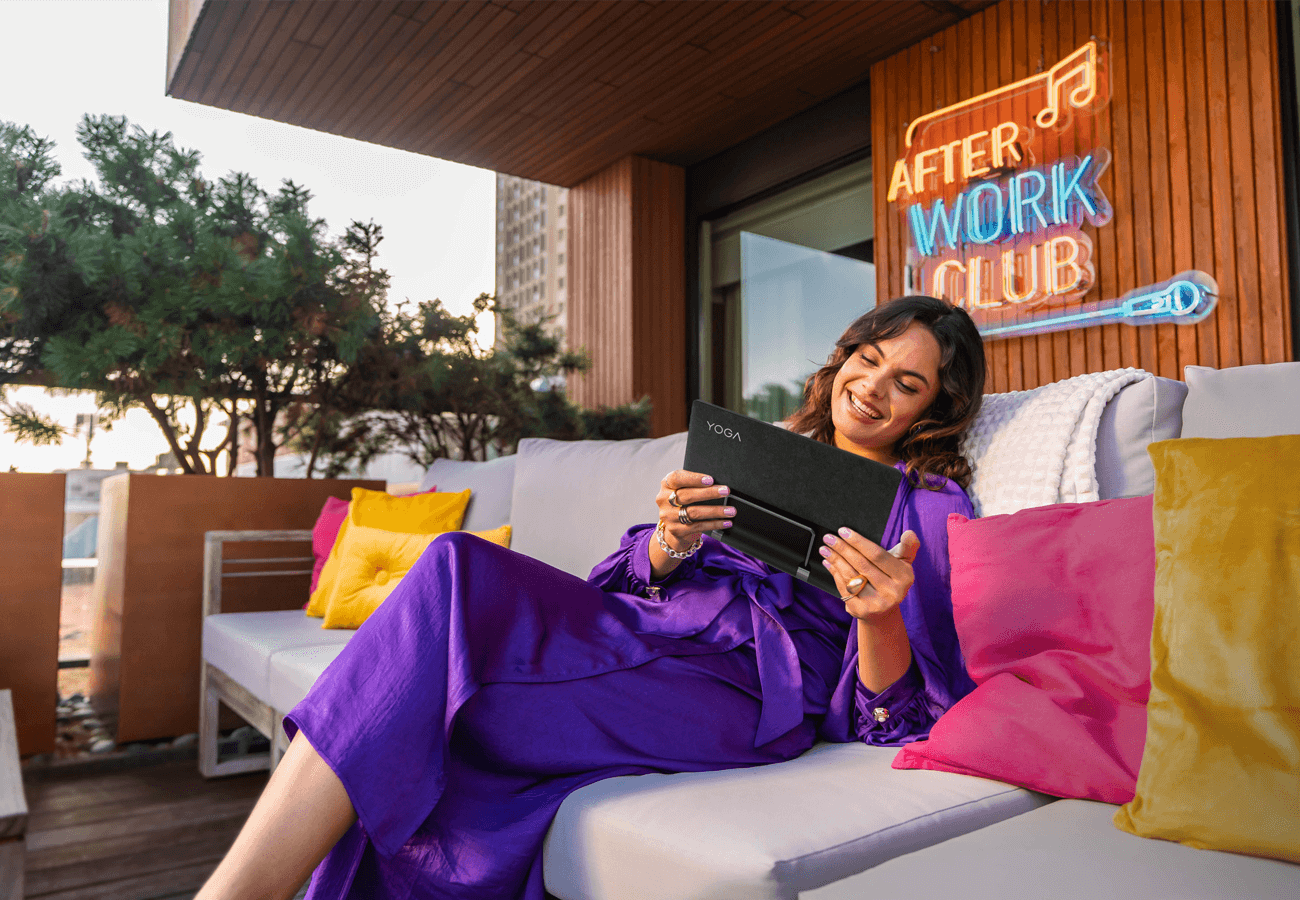 Woman relaxing on her outdoor couch, enjoying viewing content on her Lenovo Tablet.