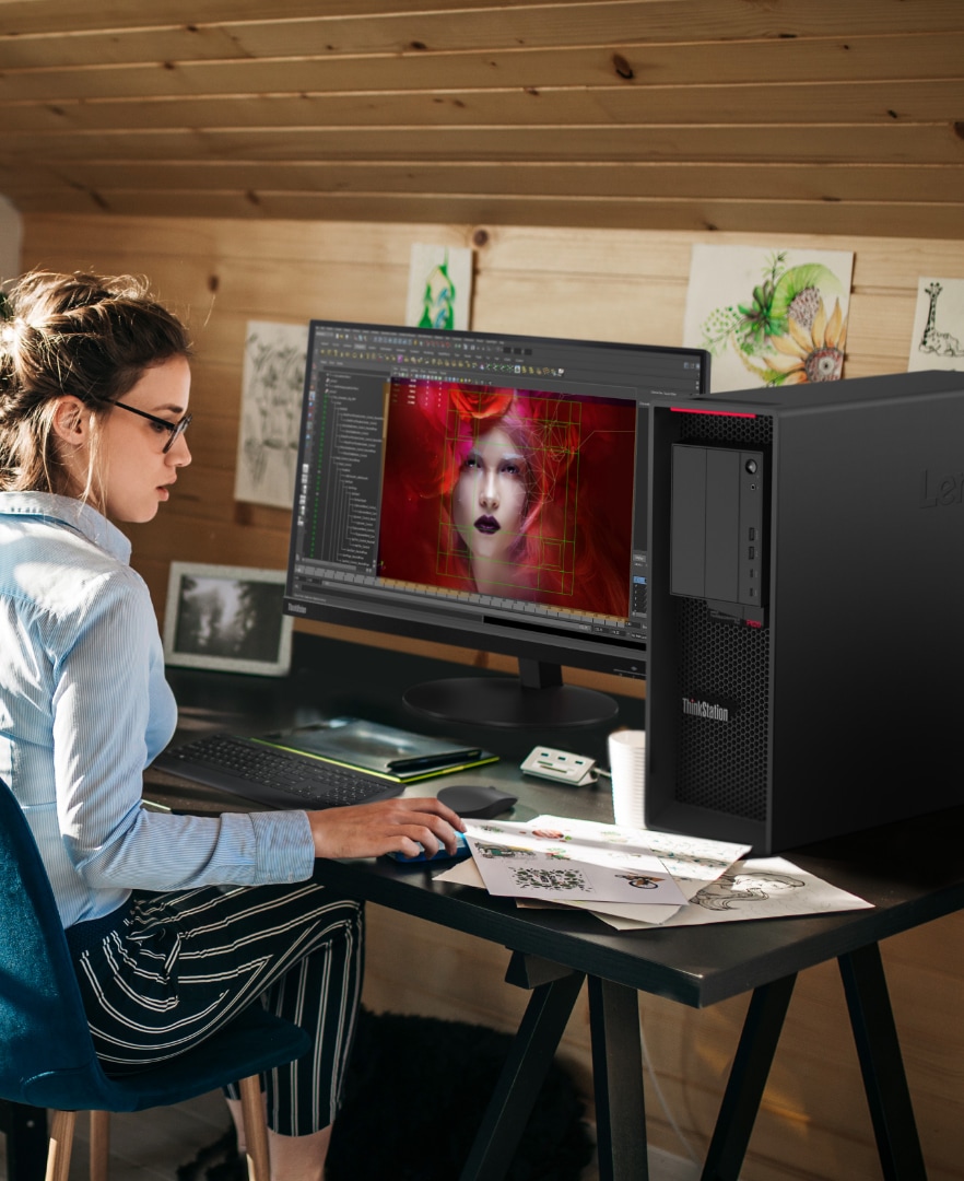 White woman at a desk using the Lenovo ThinkStation P620 tower workstation to create.