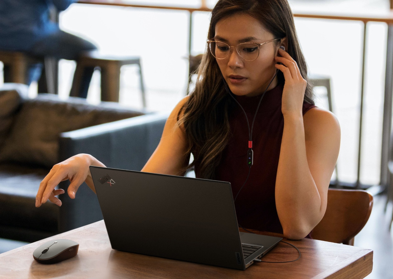 Woman using Lenovo Go accessories set up on a table at a coffee shop