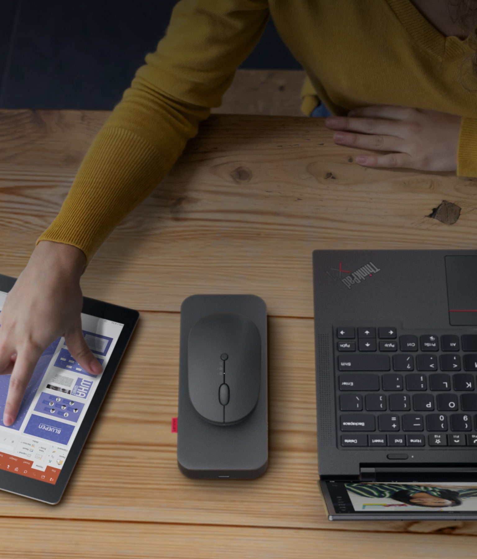 Lenovo Go Wireless Multi-Device Mouse sitting on table in front of user with tablet and ThinkPad laptop