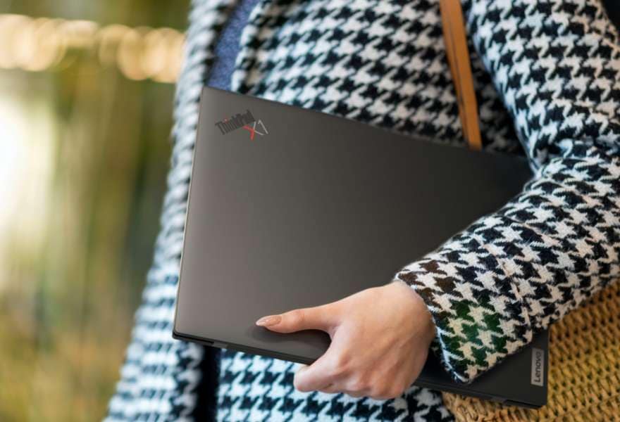 Person som bär en ultraportabel Lenovo ThinkPad X1 Carbon Gen 10 bärbar dator under armen