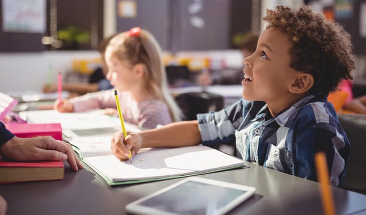 Jeune fille et jeune garçon prenant des notes sur une table dans une salle de classe