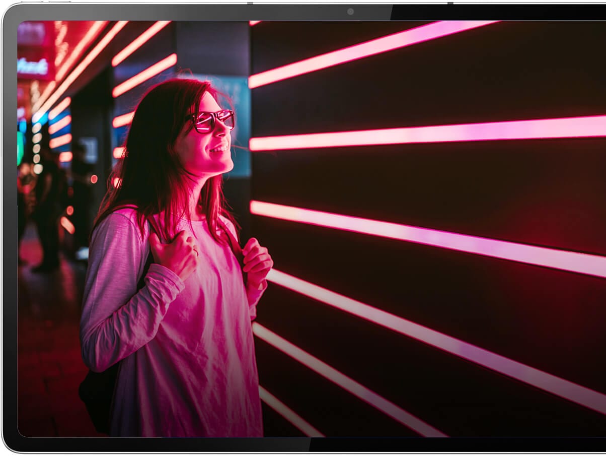 Eine Frau blickt auf eine Wand mit beleuchteten rosa Streifen