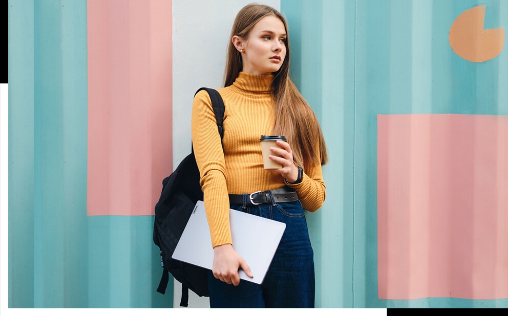 Eine junge Frau trägt ein Lenovo Notebook und einen Kaffee