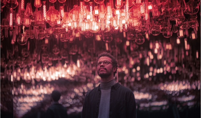 A man looking up at a ceiling lined with Edison style lightbulbs