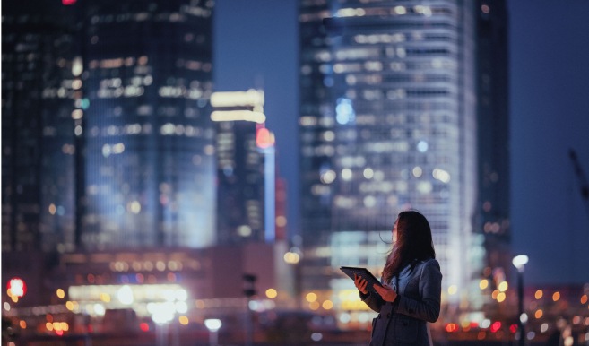 Woman holding a Lenovo Tablet with a large city scape behind her