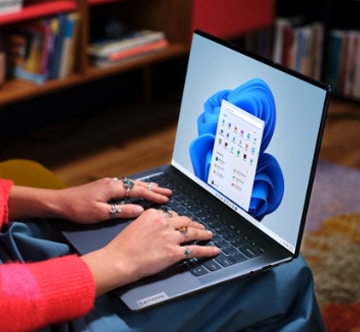 Vrouw zittend in een stoel met haar Lenovo Yoga-laptop op schoot