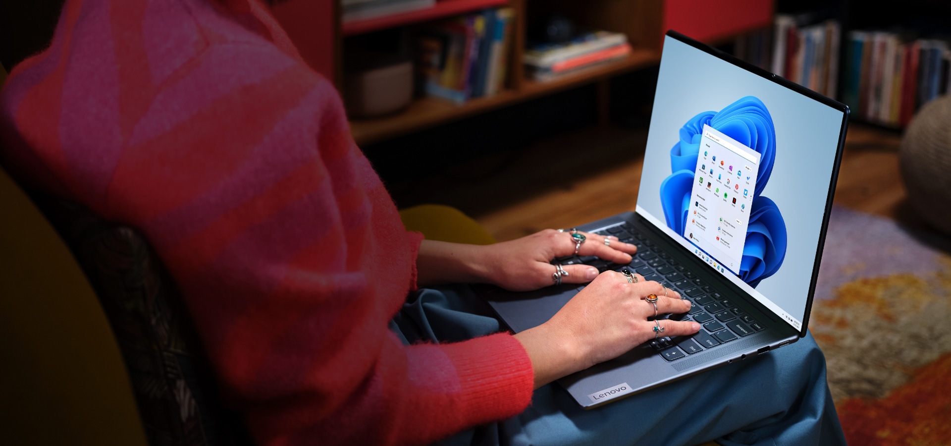 Woman sitting in a chair with her Lenovo Slim laptop sitting in her lap