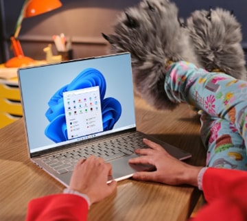 Woman in animal slippers sitting next to a small table with her Lenovo Slim laptop placed on the table