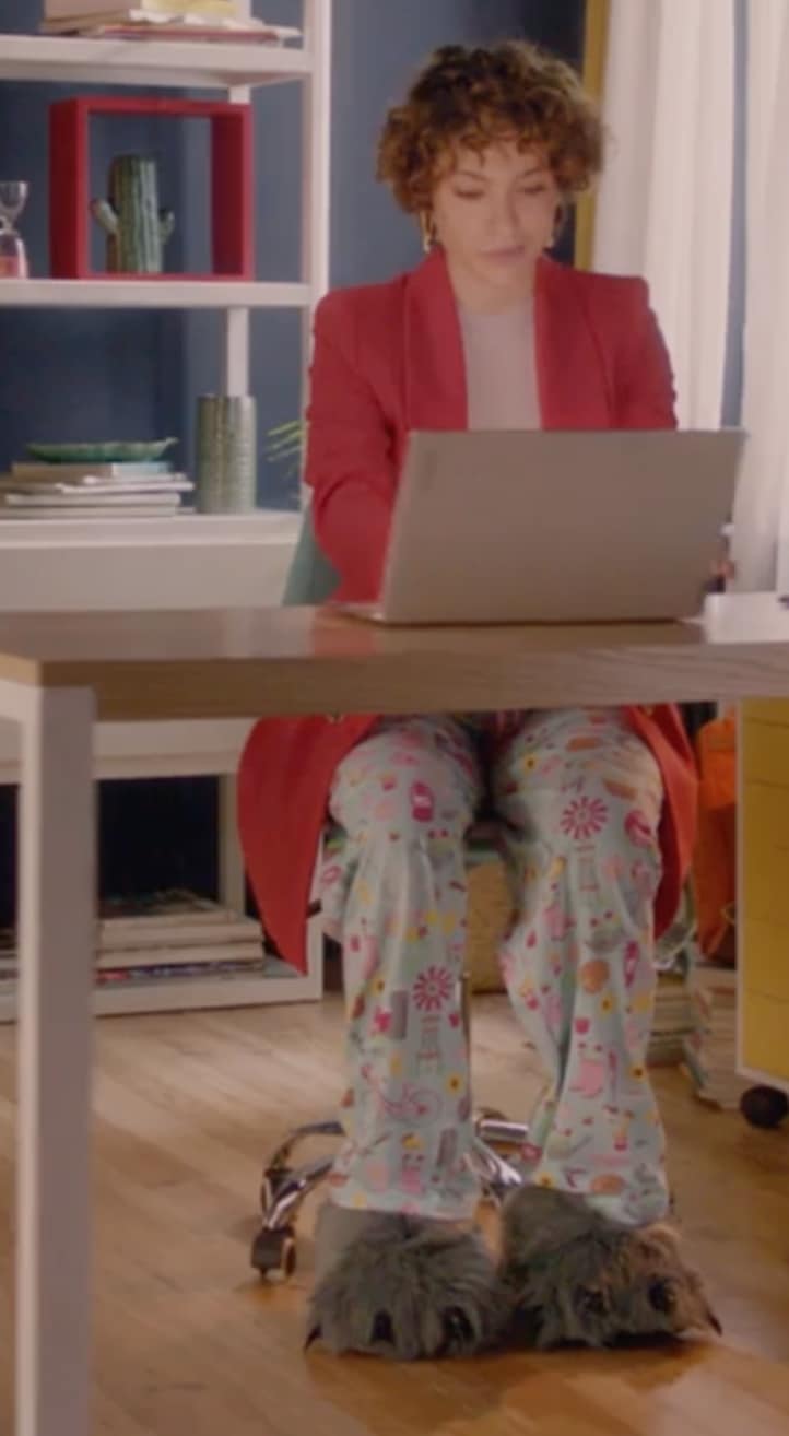 Üzerinde ceket, altında pijama ile masada oturmuş, Lenovo Yoga dizüstü bilgisayarında çalışan bir kadın