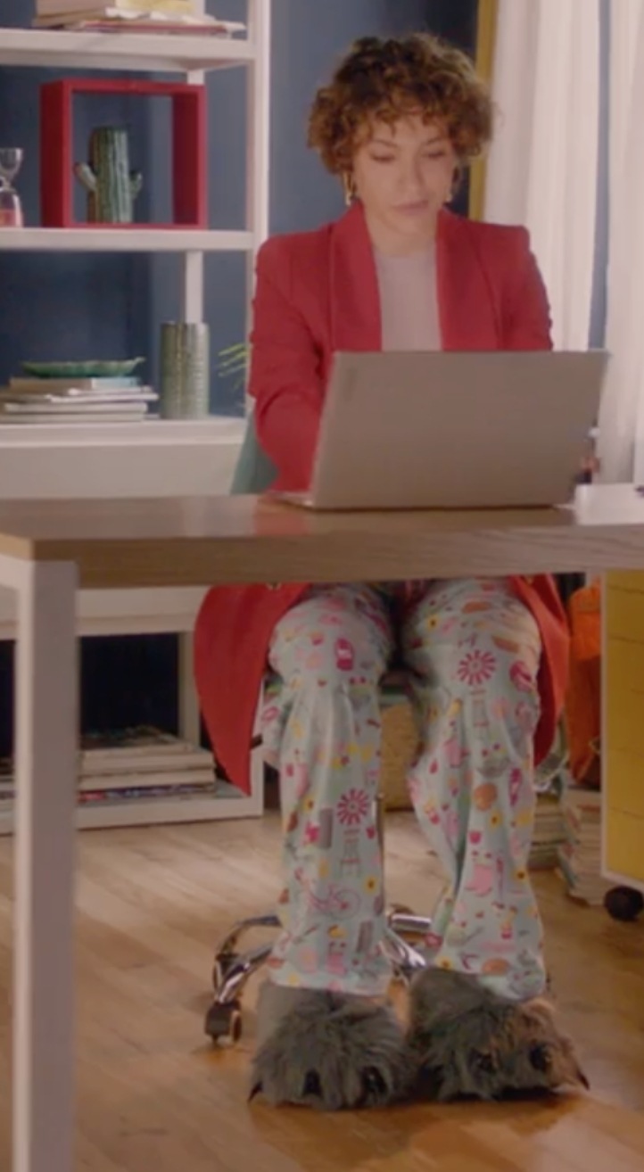 Woman in a suit top and sleep bottoms sitting at a desk with her Lenovo Slim laptop