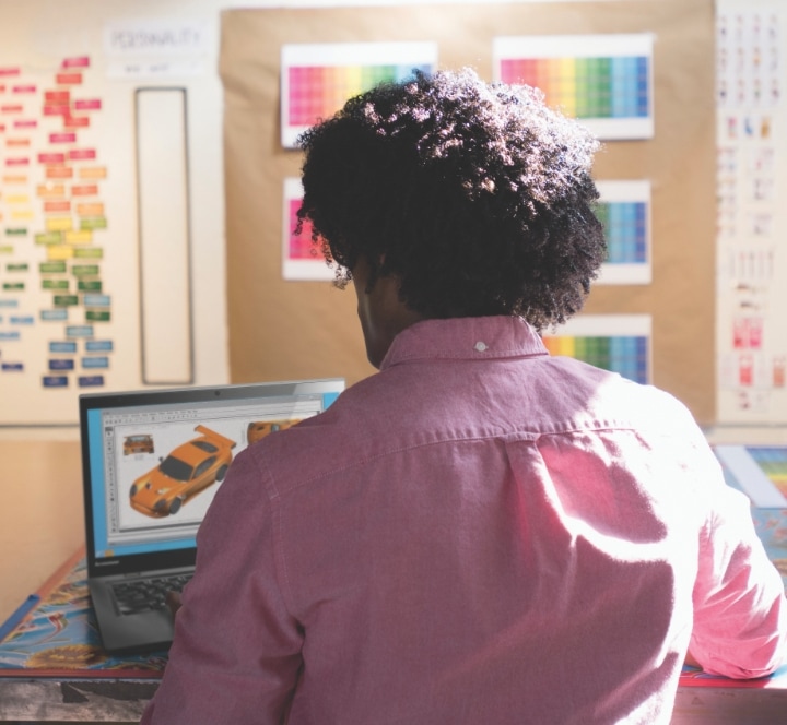 Rear view of man working on his Lenovo Yoga laptop while sitting at a desk