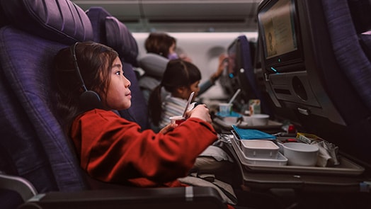 Niña en un avión entretenida por el sistema de a bordo