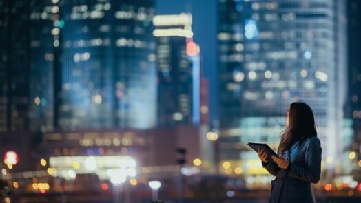Femme qui tient un carnet et regarde un paysage urbain la nuit