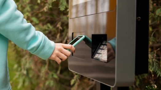 Klant die een smartphone gebruikt bij een kiosk.