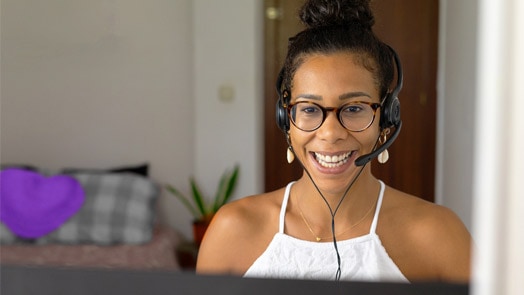 Smiling woman working from home using a laptop and headsets