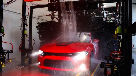 Voiture rouge passant par un lavage de voiture