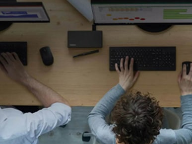 People at a desk typing on a keyboard