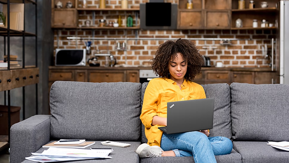 Person sitting on couch using Lenovo laptop