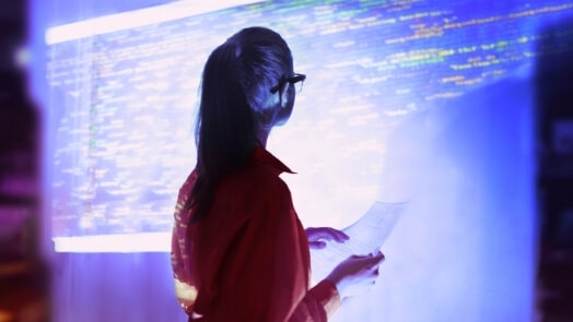 Woman looking at digital wall of code