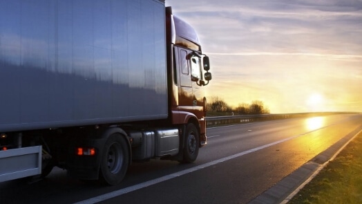 Vrachtwagen rijdt bij zonsondergang of zonsopgang op een snelweg