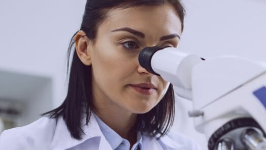Researcher looking through a microscope.