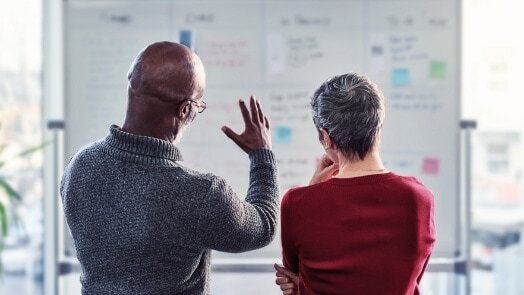 Twee mensen werken samen aan een whiteboard