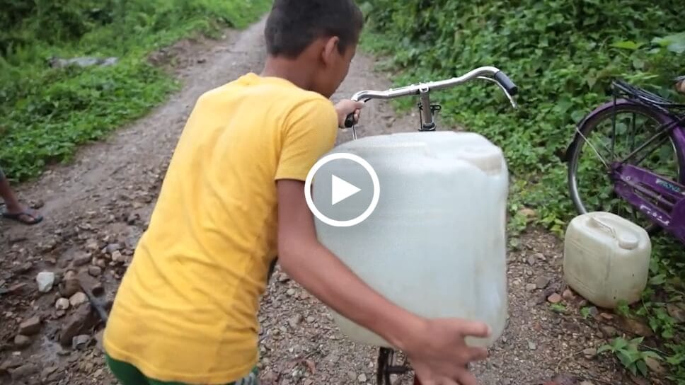 Boy carrying water on a bicycle