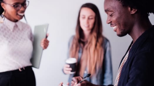 Tres profesionales trabajando en colaboración, con uno de ellos tomando apuntes