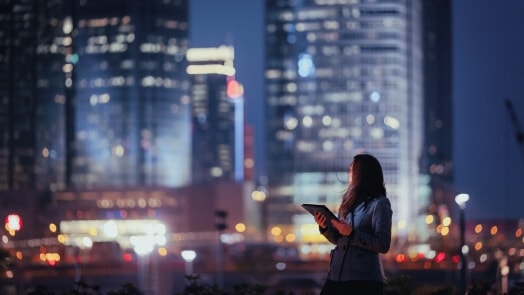 Femme avec un portable, silhouette à contre des bâtiments urbains